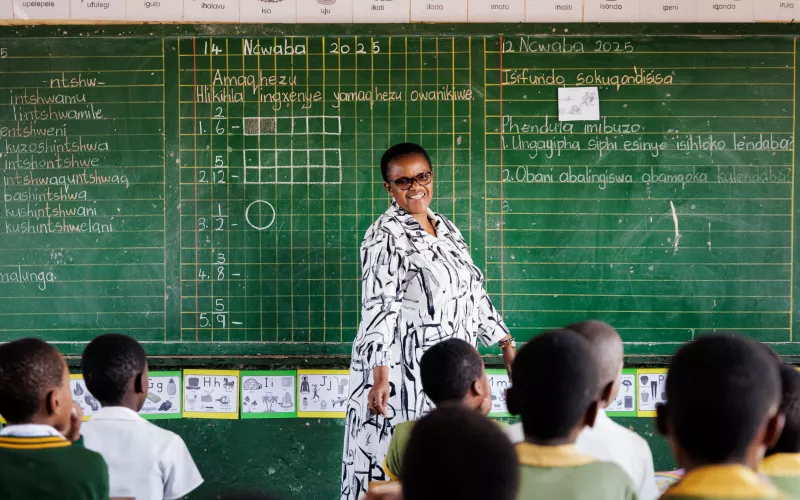 A female teacher in South Africa standing in front of a blackboard teaching her students.