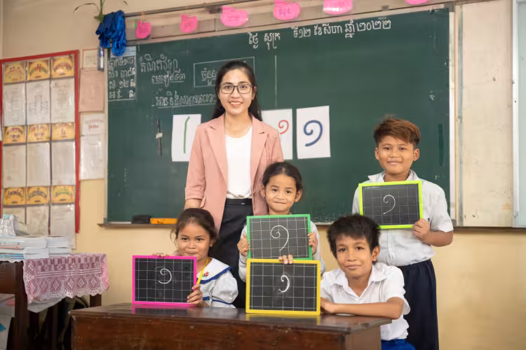 A teacher and four smiling students hold chalkboards with maths equations. 