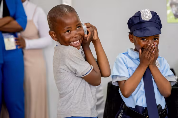 Smiling children role play different jobs such as police officer in South Africa, showing gender shouldn't matter in jobs.