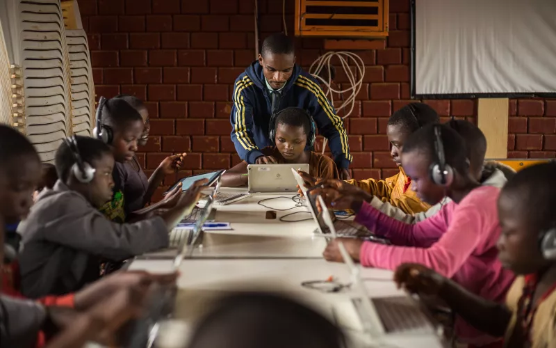 Children surfing on tablets, under the guidance of Alexis Nimubona, the facilitator in charge of the Ideas Box at the center. Credit: Kibuuka Mukisa Oscar / AFD