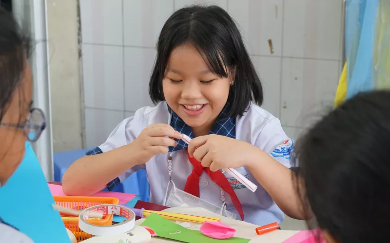Vietnamese student enjoys playing with coloured papers and art supplies
