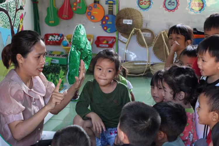 A Vietnamese teachers interacts with young learners in a classroom