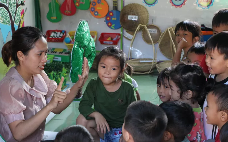 A Vietnamese teachers interacts with young learners in a classroom
