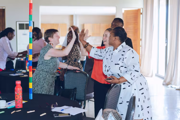 Participants share a high-five during a playful workshop activity with colourful building blocks.