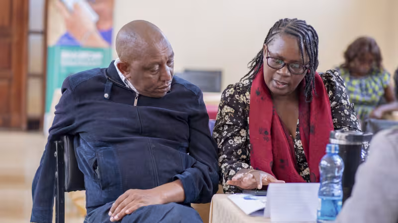 Two workshop participants sit together and discuss materials during a group activity.
