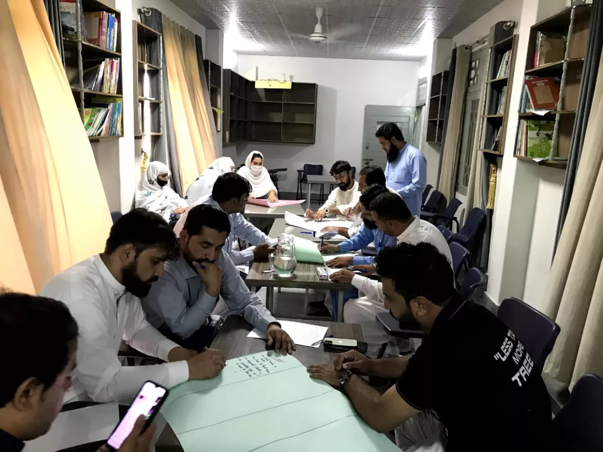 A group of men sit a tables and look at their phones.