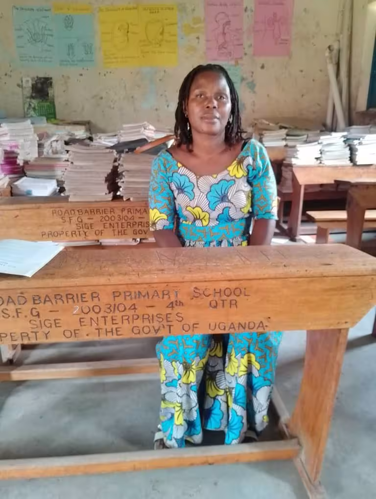 Sarah is sitting in a classroom, wearing a long blue dress.
