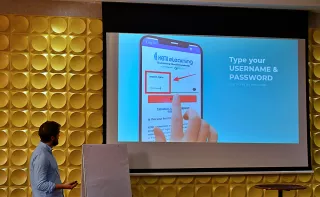 A person stands in front of a screen showing a smartphone login page. The text reads "Type your USERNAME & PASSWORD."