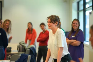 A group of five people are gathered in an office, engaged in conversation and laughter.