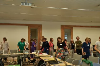 A group of people standing and interacting in an office. 