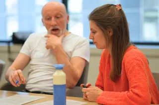 A man speaking while a woman is listening. 