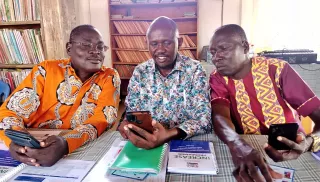Three men looking at a phone.