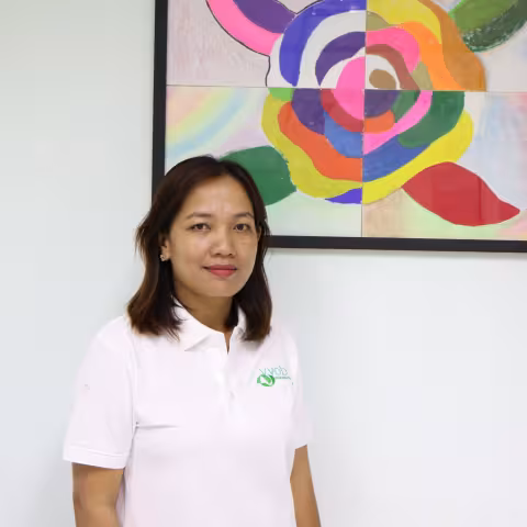 Sokaylan wearing a white VVOB polo shirt, standing in front of a colourful abstract painting.