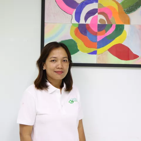 Sokaylan wearing a white VVOB polo shirt, standing in front of a colourful abstract painting.