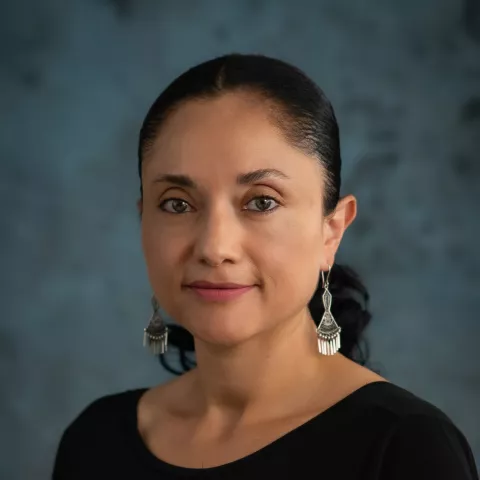 Maribel smiles softly while wearing a black shirt. 