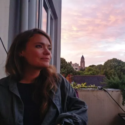 Steffi looks away from the background. The background is a purple sunset.