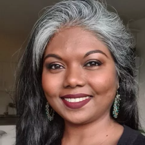 Asmita is wearing earrings and a black top.