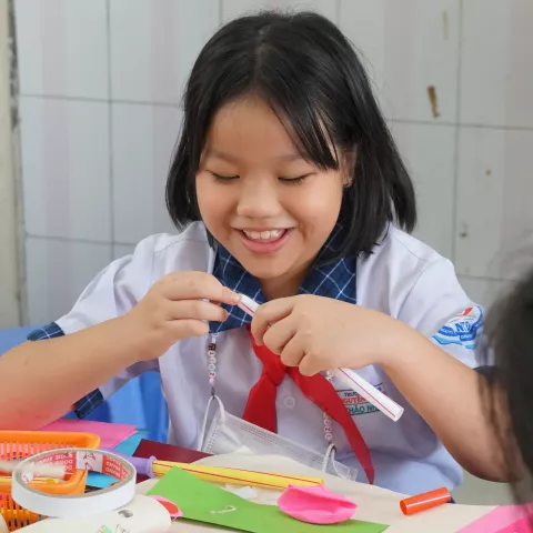 Vietnamese student enjoys playing with coloured papers and art supplies