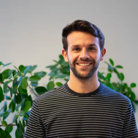 Dimitrios is smiling, a plant behind him.