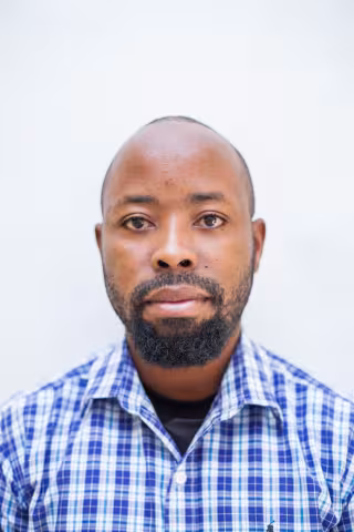Frank is wearing a checkered shirt. The background is plain white.