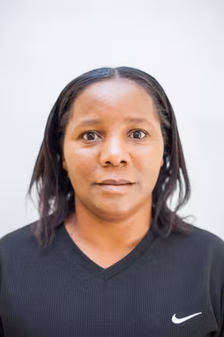 Getrude is wearing a black top. The background is plain white. 