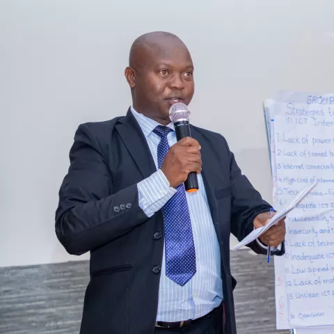 Stephen, a school leader in Kenya, stands with a mic in hand