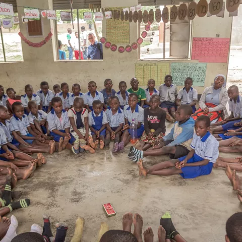 Primary school learners sit in a circle during a classroom activity focused on group participation