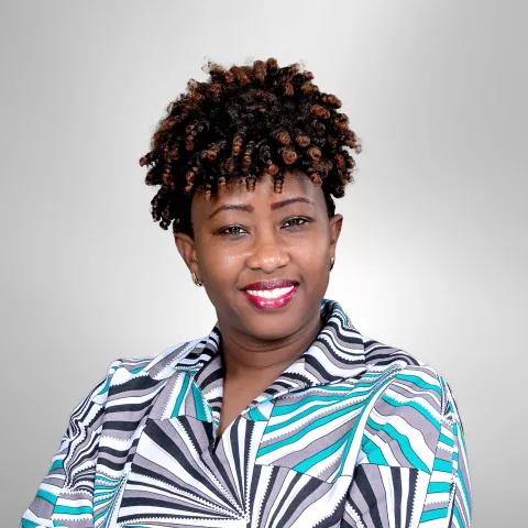 Louisa is in a striped shirt with teal accents against a gray background.