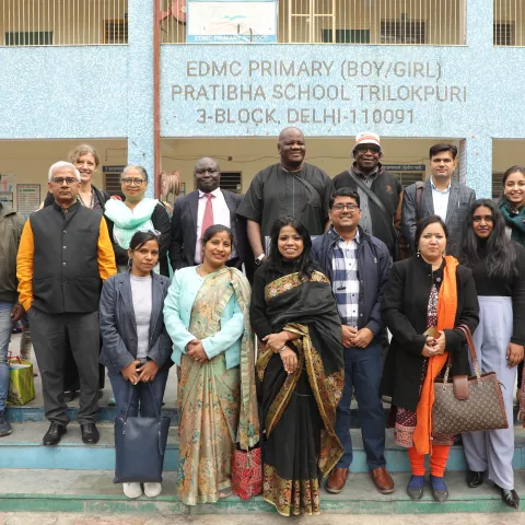 Group photo of people standing outside a school in Delhi, India.