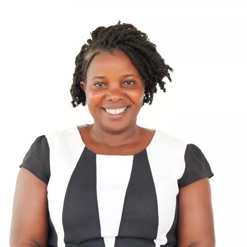 Miriam is wearing a black and white striped dress, standing against a plain white background.