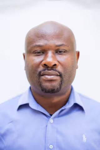 Roy is wearing a blue shirt against a plain white background. 