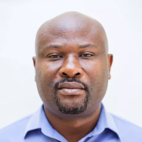 Roy is wearing a blue shirt against a plain white background. 