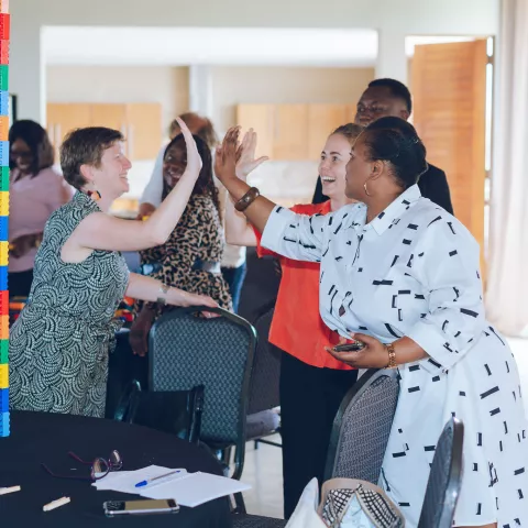 Participants share a high-five during a playful workshop activity with colourful building blocks.