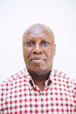 Stephen is wearing checkered red and white shirt against a plain white background.