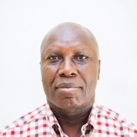 Stephen is wearing checkered red and white shirt against a plain white background.