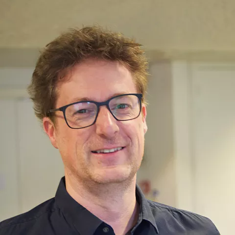 Sven is wearing glasses and is smiling at the camera