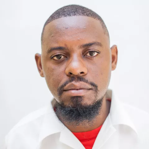 Sydney is wearing a white shirt over a red top. The background is plain white.