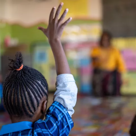 A schoolgirl raises her hand in a classroom in Zambia